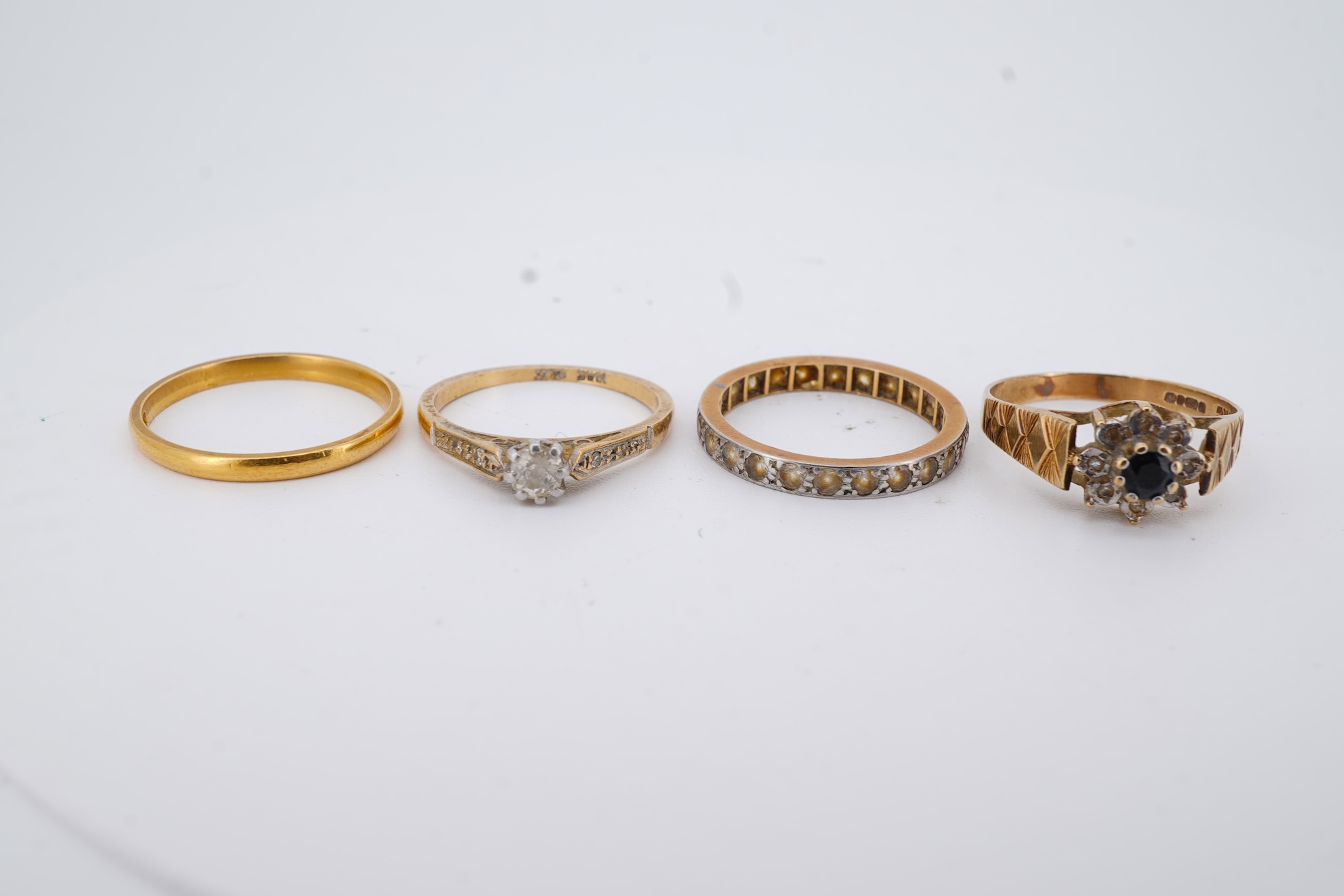 A 22ct wedding band, size M, 2 grams, an 18ct, plat and single stone diamond ring, a a modern 9ct gold, sapphire and diamond cluster ring and a yellow metal and white stone, eternity ring.